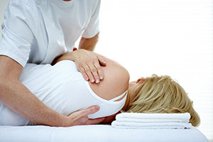 Male osteopath treating back problem of a woman